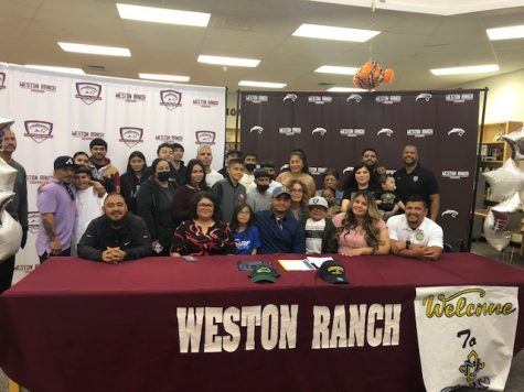 Senior Jesus Gonzales signs his letter surrounded by his family and friends